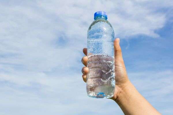 Botella de agua y mochila sobre una banca en un parque